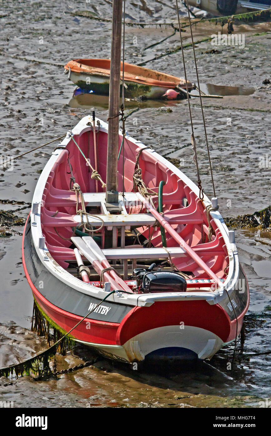 Il coble 'Whitby" si siede a terra in corrispondenza di suoi ormeggi su un letto di sabbia fangoso a bassa marea in Scarborough Harbour. Foto Stock