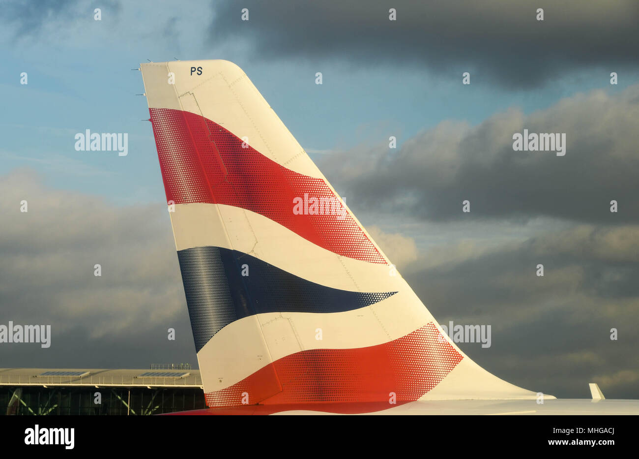 In prossimità della coda di un British Airways Airbus a getto di passeggeri all'Aeroporto di Londra Heathrow contro un cielo nuvoloso scuro Foto Stock