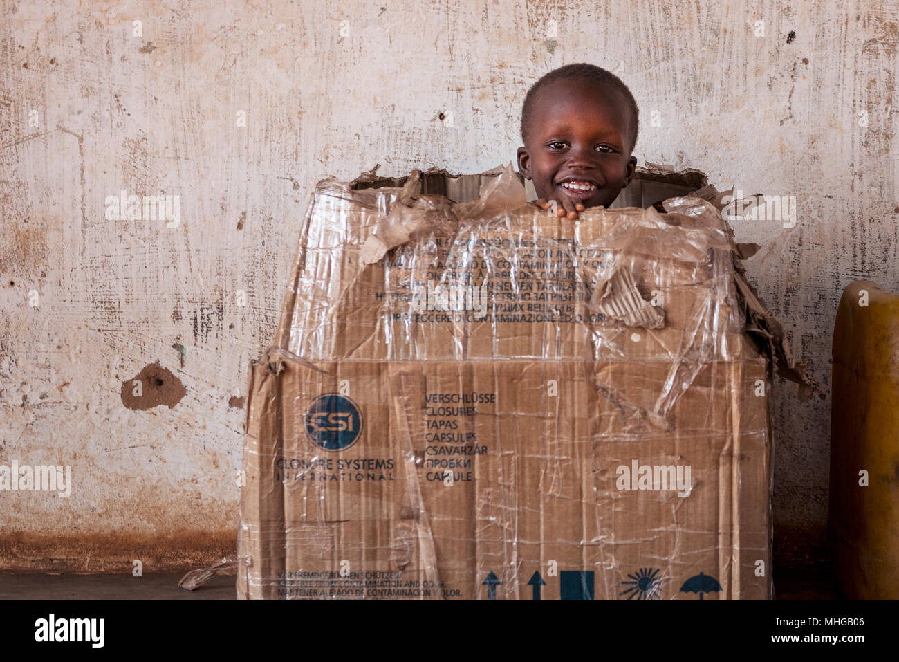 Nhacra, Repubblica di Guinea Bissau - Gennaio 28, 2018: Ritratto di una giovane ragazzo giocando in una scatola di carta nella città di Nhacra in Guinea Bissau, West Afric Foto Stock