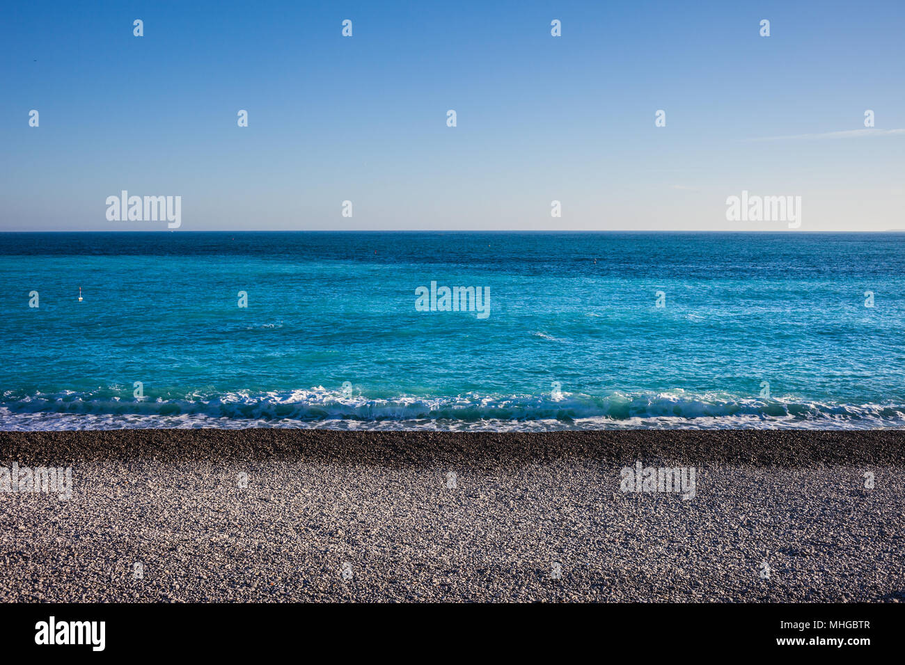 Spiaggia di ciottoli e il mare sullo sfondo di una giornata soleggiata con cielo chiaro nella bella città sulla Costa Azzurra in Francia, Europa Foto Stock