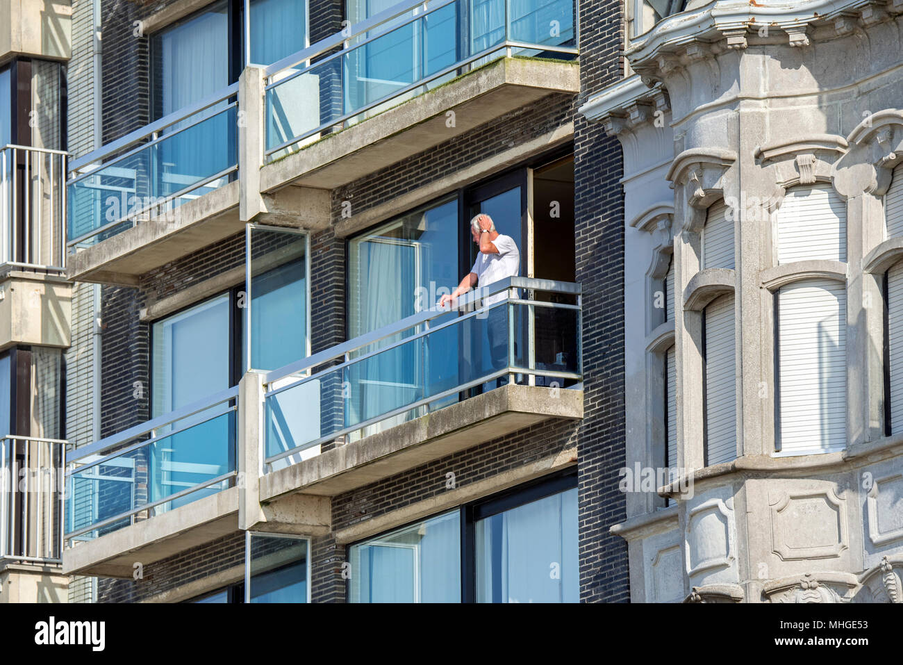 Uomo anziano in piedi sul balcone del moderno appartamento / appartamento Foto Stock