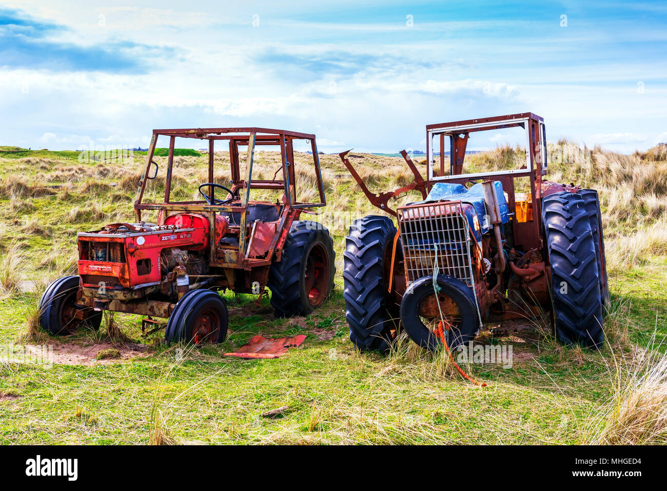 Due vecchi e abbandonato i trattori agricoli in un campo nei pressi di Goswick, Northumberland, England, Regno Unito Foto Stock