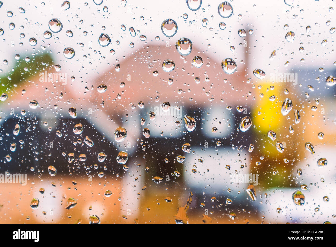 Abstact colorati di immagine sfocata case attraverso una finestra con gocce di pioggia. La riflessione delle case può essere visto in le gocce di acqua Foto Stock