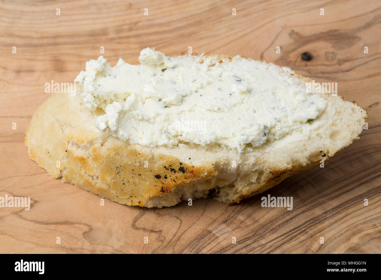 Francese di formaggio Boursin acquistato da un supermercato nel Regno Unito spalmato su una fetta di pane bianco. Boursin è un pieno di grasso morbido formaggio di latte di mucca flav Foto Stock