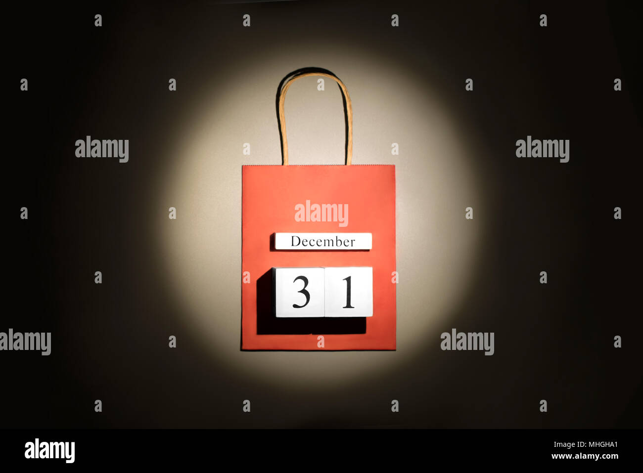 Red shopping bag con il nuovo anno il 31 di dicembre data nel raggio del punto panoramico luce su sfondo scuro. Foto Stock