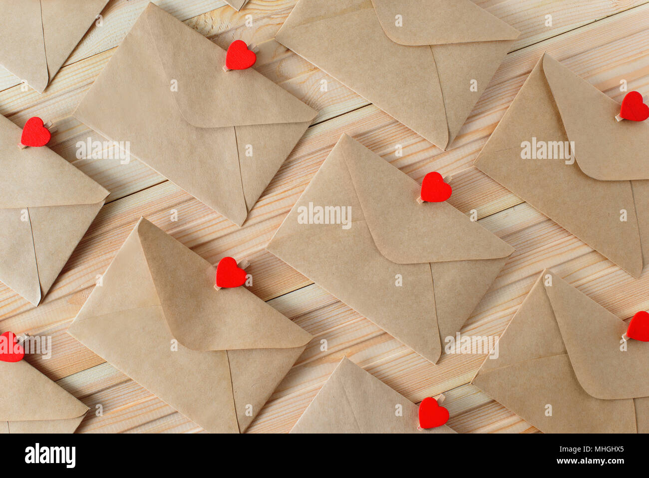 Buste di carta artigianale con cuore rosso pin sullo sfondo di legno. Foto Stock