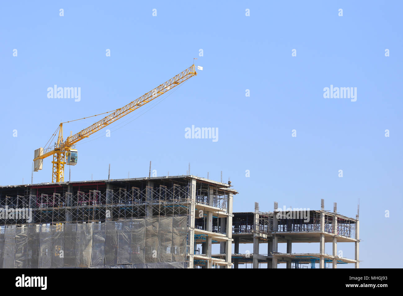 Grande gru di pesanti macchinari di fabbrica o edificio condominiale sul cielo blu sullo sfondo. Foto Stock