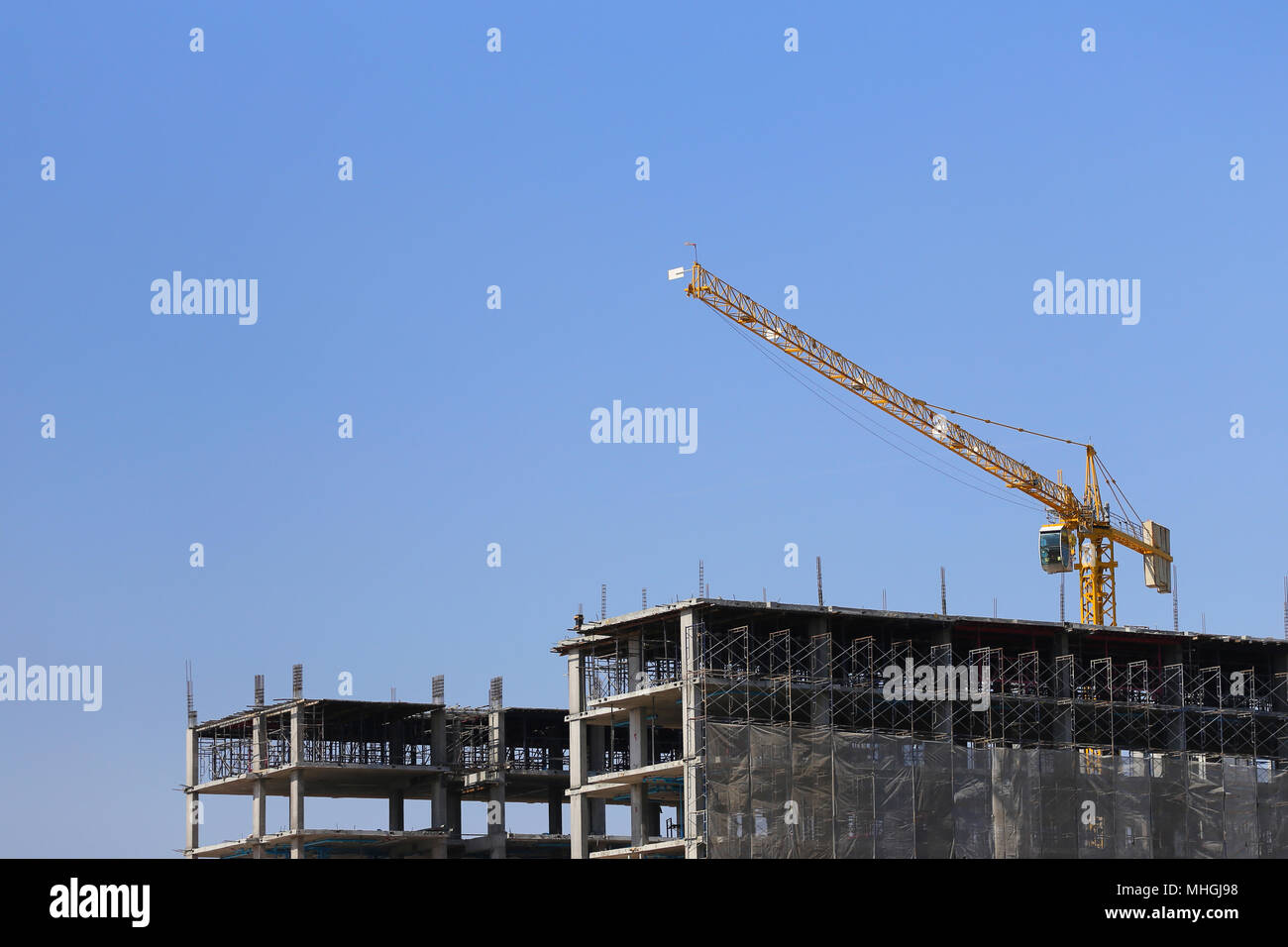 Grande gru di pesanti macchinari di fabbrica o edificio condominiale sul cielo blu sullo sfondo. Foto Stock