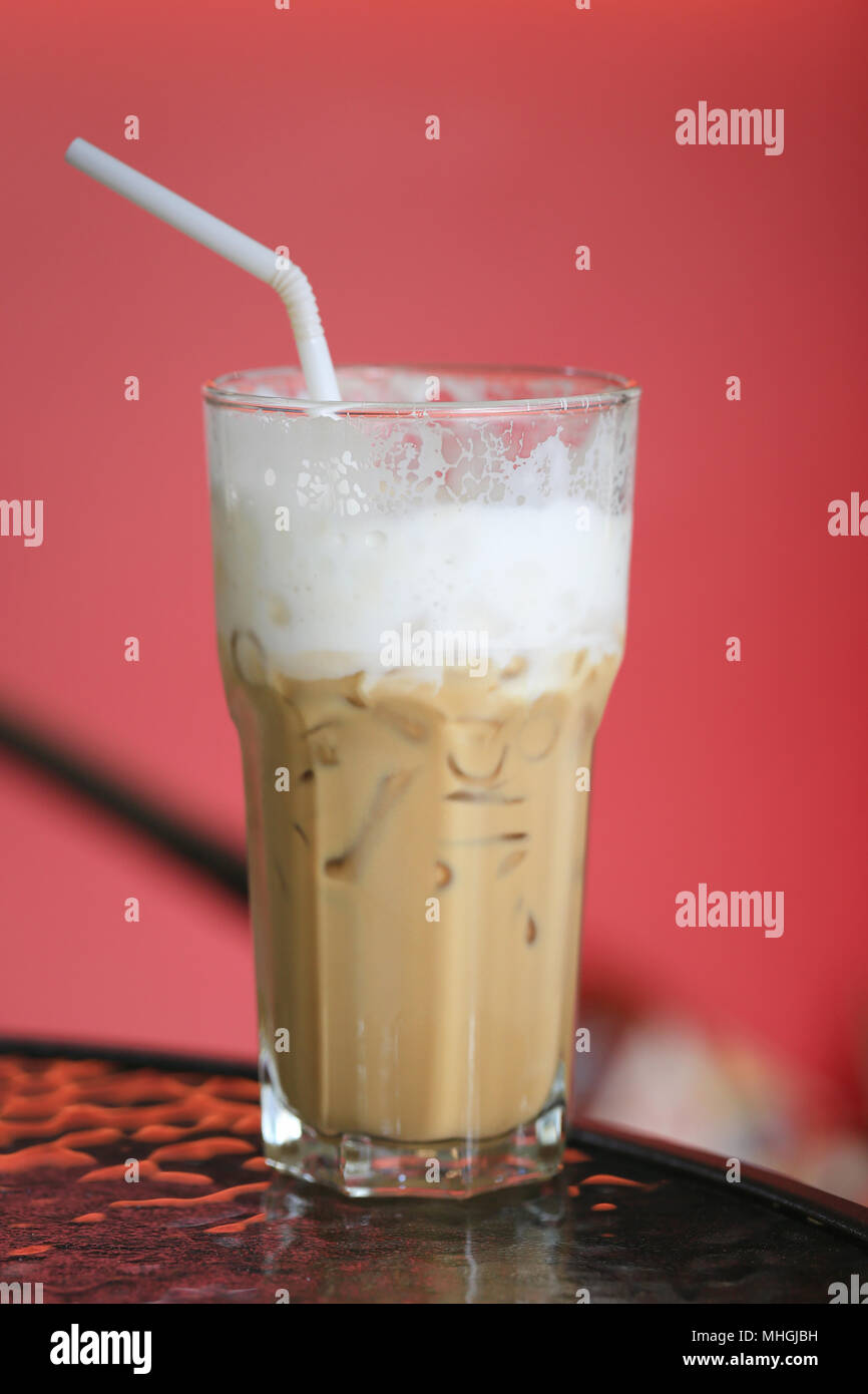 Raffreddare il caffè in un bicchiere con un tubo bianco su una tabella degli alimenti in coffee shop. Foto Stock