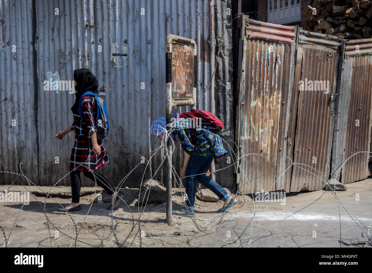 Musulmani del Kashmir ragazze giovani attraversare un filo spinato barricade prevista dalla Indian forze armate durante le restrizioni nell'area del centro cittadino di Srinagar città, capitale estiva del Jammu e Kashmir. Le autorità indiane martedì imposto restrizioni in molte parti di Srinagar città per evitare scontri e proteste in valle a seguito di una chiamata di protesta dal JRL (resistenza comune di Leadership) contro l uccisione di uno studente Shahid Ashraf Dar e due gruppi ribelli locali Sameer Ahmad e Aqib Wani da Indian forze armate e ferendo più di 50 innocenti cittadini disarmati con proiettili e agglomerati in forma di pellets e scatenando un regno di ter Foto Stock