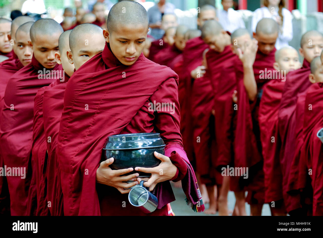 MYANMAR, AMARAPURA - Giugno 28, 2015: i monaci buddisti coda per il pranzo nella parte anteriore del monastero Mahagandayon il 28 giugno 2015 in Amarapura. Foto Stock