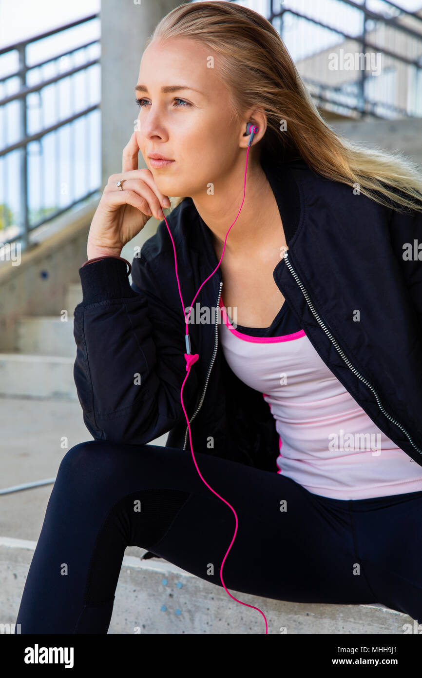 Montare pensosa donna Ascoltare musica mentre è seduto sui gradini Foto Stock