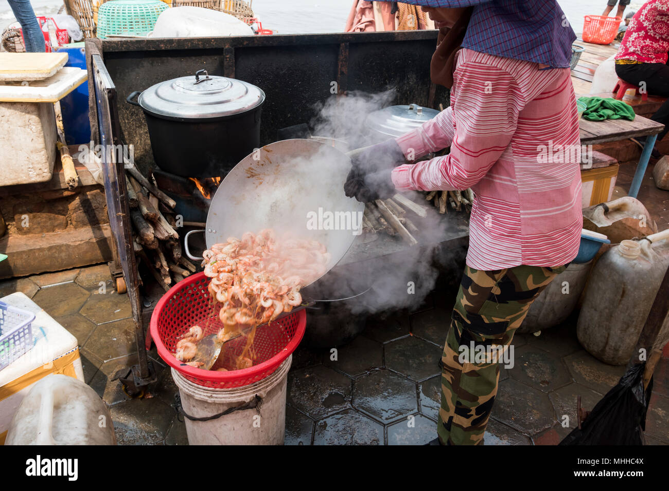 Una signora cambogiana prepara i gamberi in una cucina rustica, offrendo uno scorcio sull'autentica cucina locale e sulla vita locale nella provincia cambogiana del KEP Foto Stock