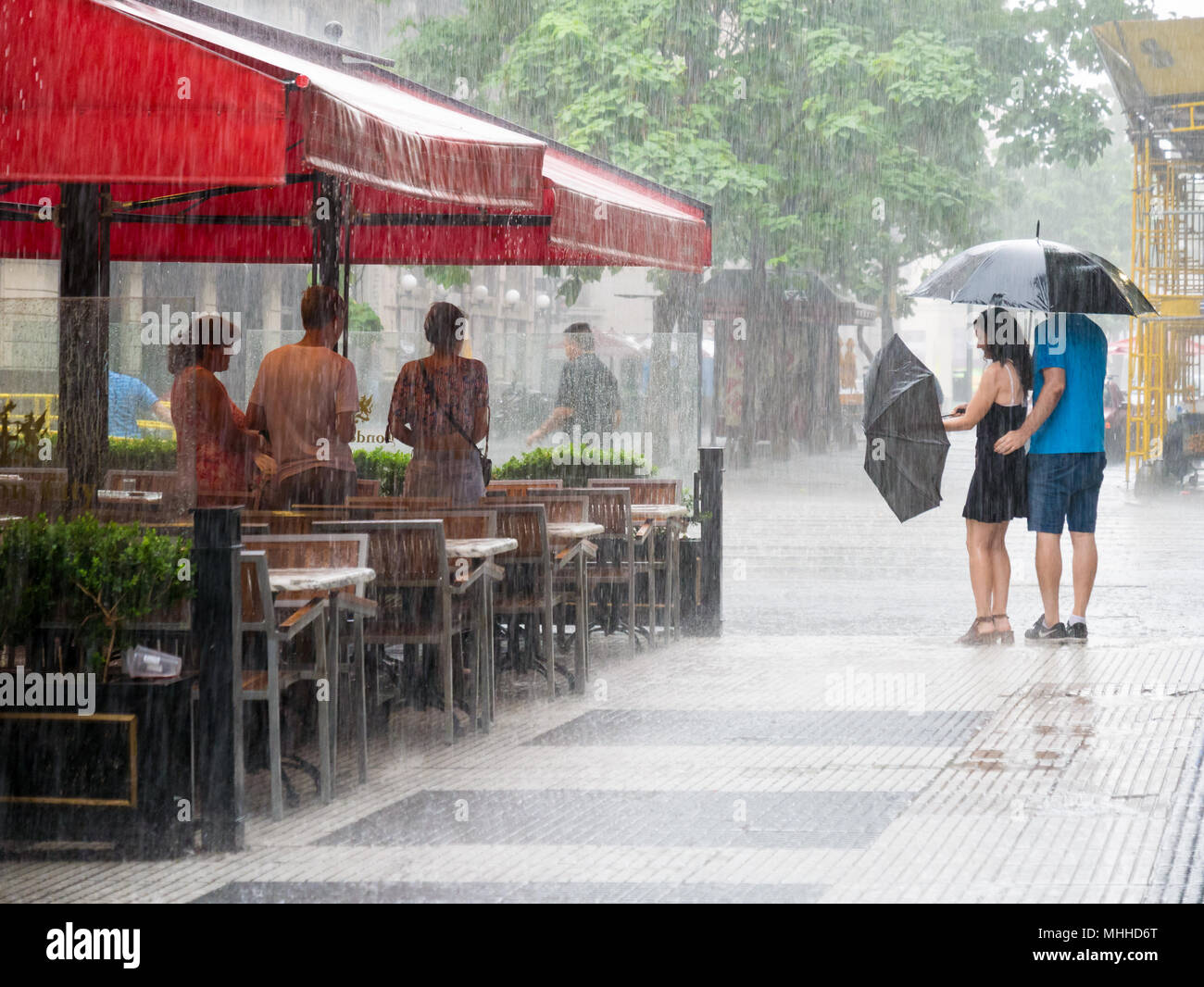 La gente si ripara dalla pioggia forte e matura con ombrello nel centro di Buenos Aires, Argentina Foto Stock