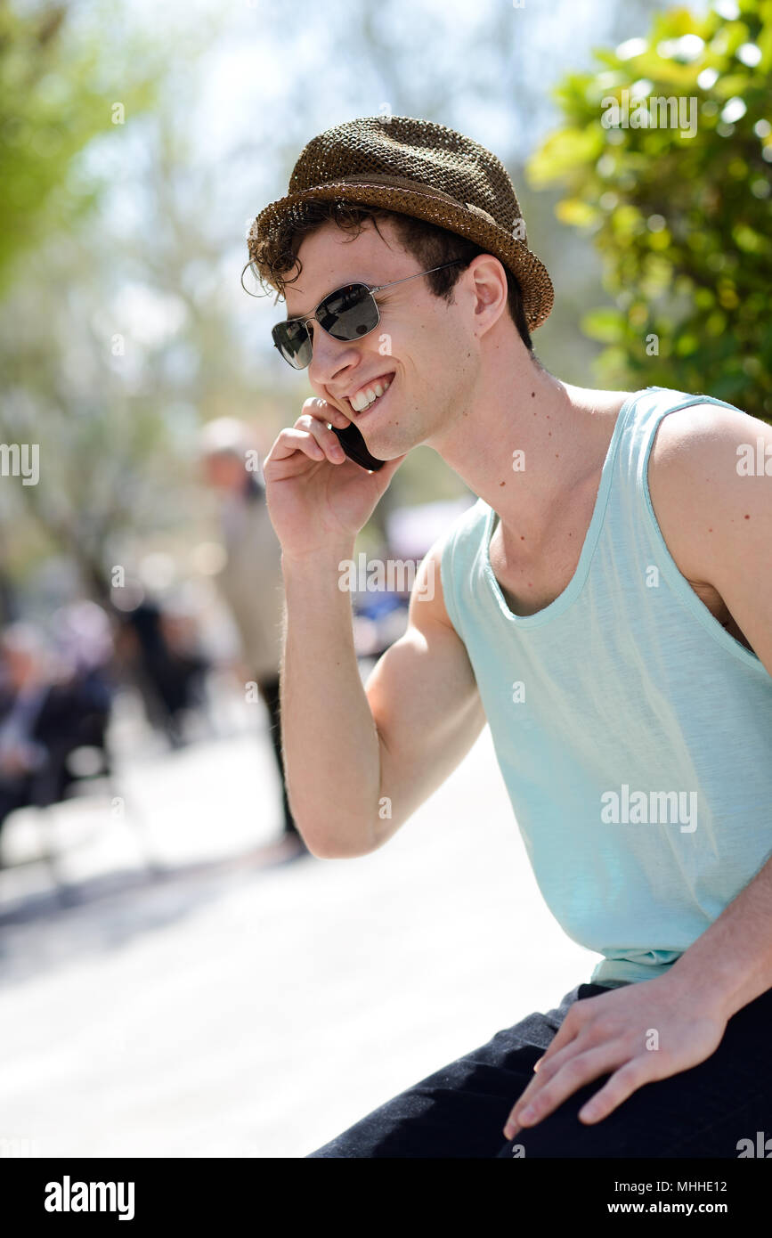 Ritratto di un giovane attraente uomo che indossa hat parlando al telefono cellulare Foto Stock