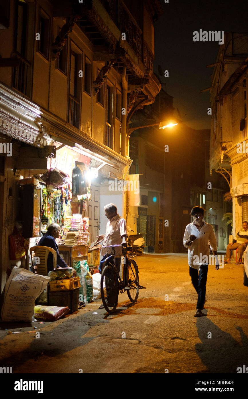 Uomo al telefono nella parte anteriore di un tuk tuk. La strada dello shopping di strade affollate nella parte vecchia della città di Ahmedabad, Manek Chowk. Foto Stock