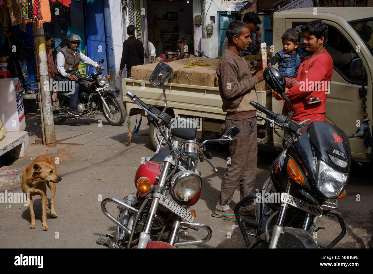 Due uomini e un bambino a parlare come la vita continua intorno a un angolo di strada. Udaipur, conosciuta anche come la Città dei laghi, la Venezia dell'Est, è la capitale storica del regno di Mewar, Rajasthan. Foto Stock