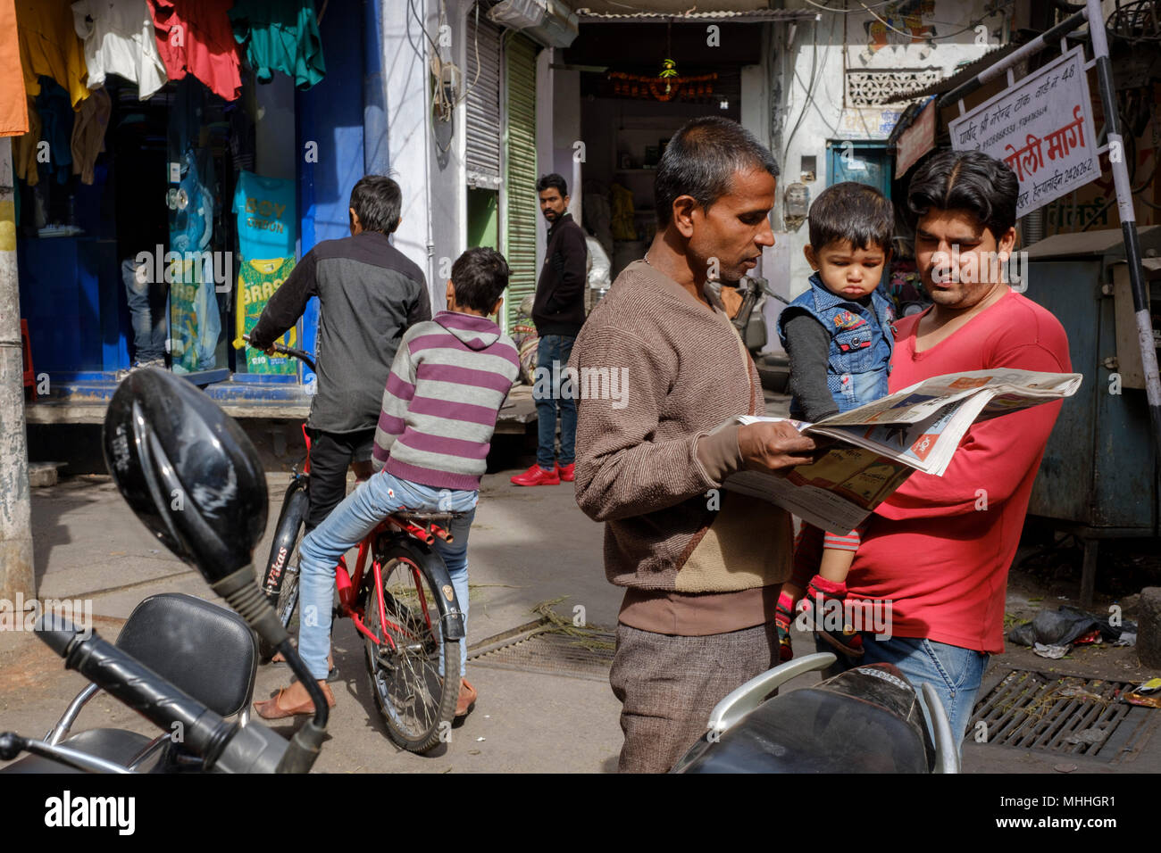 Due uomini e un bambino a parlare come la vita continua intorno a un angolo di strada. Udaipur, conosciuta anche come la Città dei laghi, la Venezia dell'Est, è la capitale storica del regno di Mewar, Rajasthan. Foto Stock