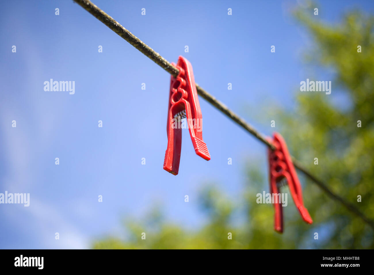 Due clothespins rossa su uno stendibiancheria in un cielo blu Foto Stock