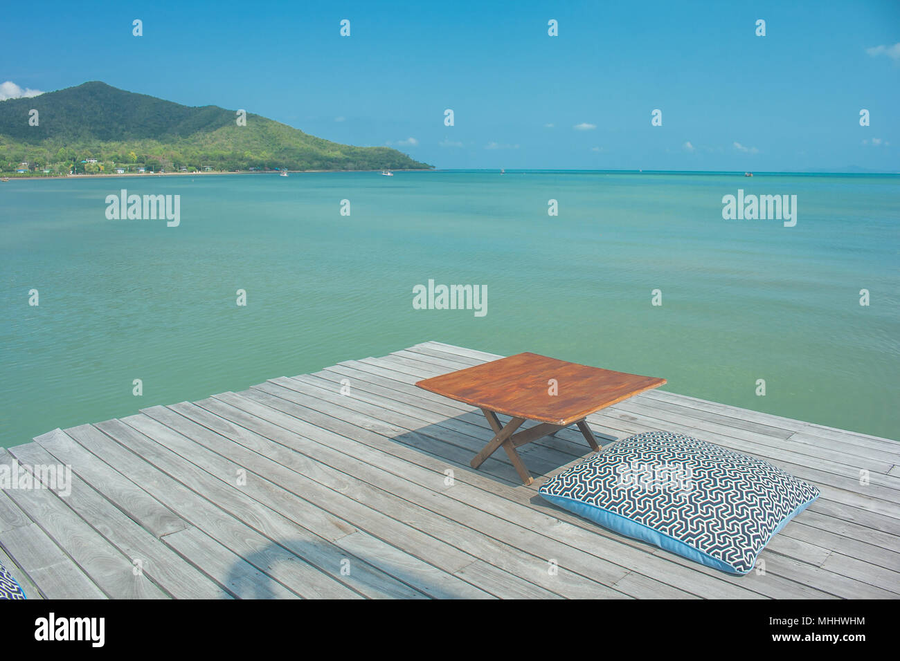 La vacanza estiva e il concetto di vacanza : viaggio estivo al mare, cuscini e tavolo in legno sulla terrazza all'aperto per il relax con splendida vista mar. Foto Stock