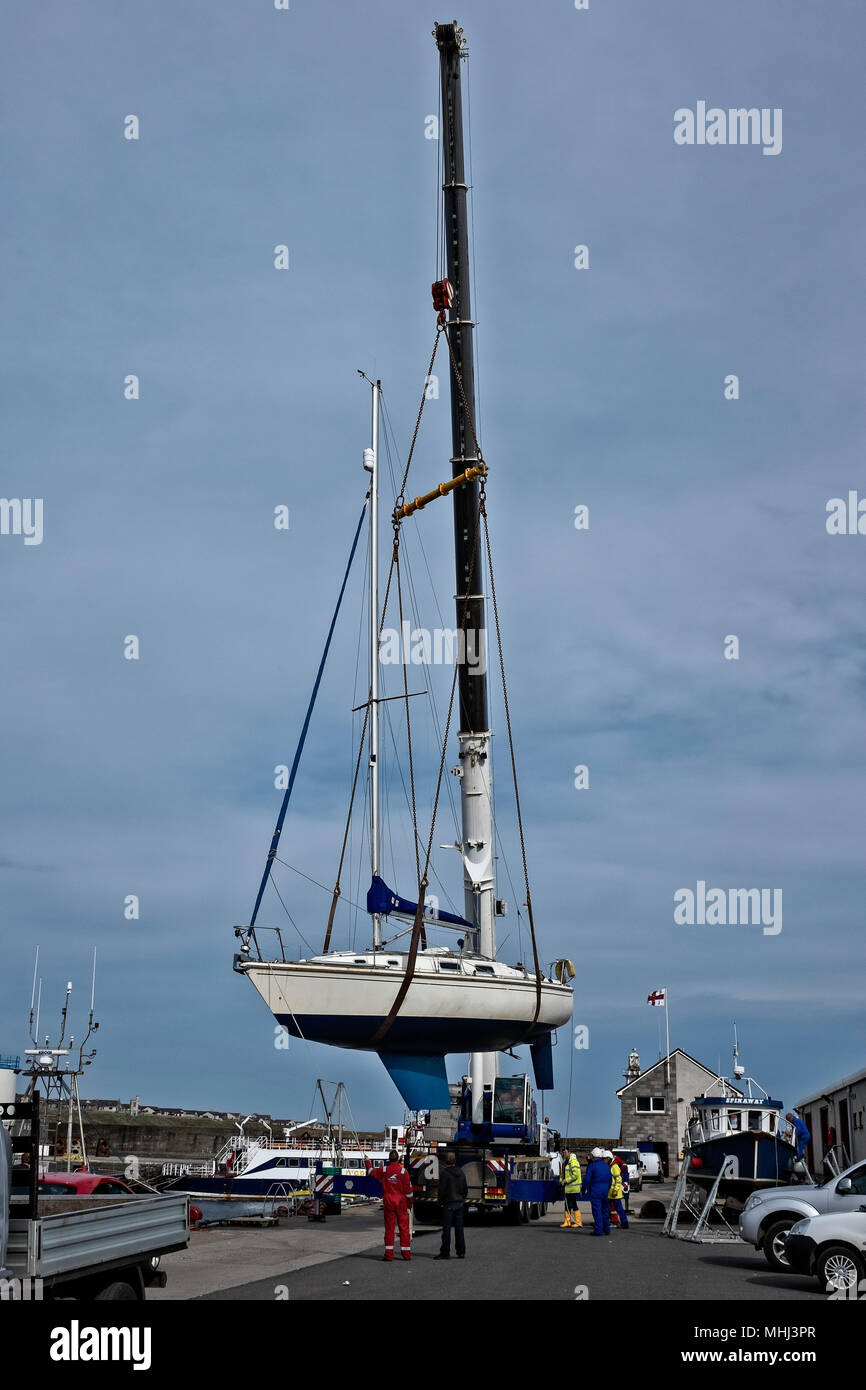 La trinità unico masted imbarcazione a vela è sollevato nel porto di stoppino da una strada andando pesante gru di sollevamento Foto Stock