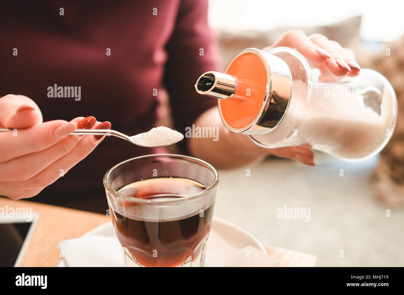 Femmina versa a mano per lo zucchero nel caffè caldo. Pranzo di lavoro Foto Stock