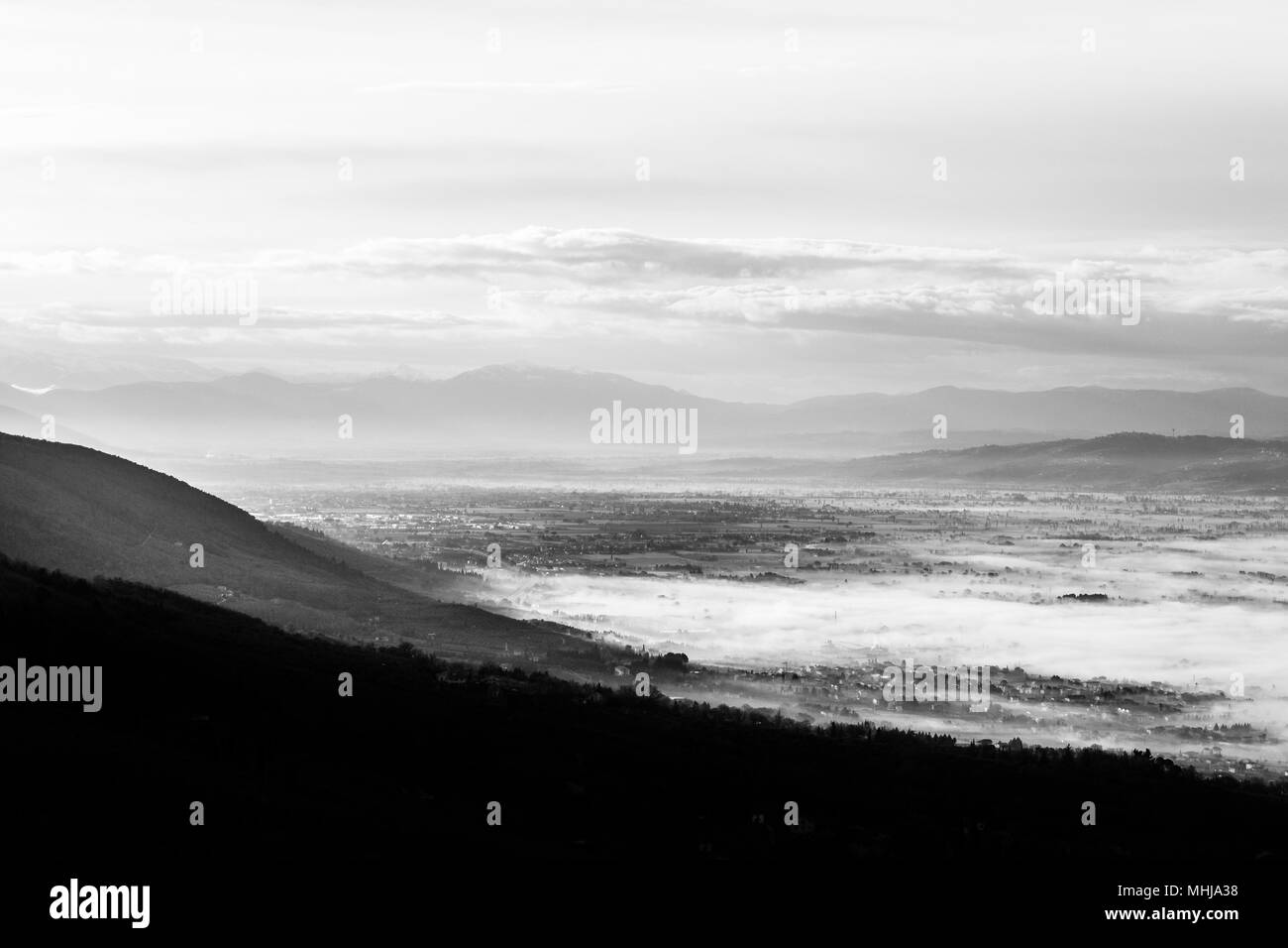 Splendida vista della valle umbra in un inverno mattina, con la nebbia che copre gli alberi e le case Foto Stock