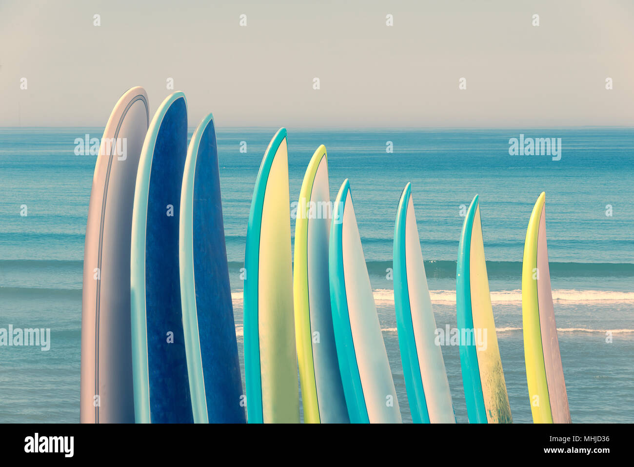 Pila di surfboads colorati su sfondo oceano con onde, retro vintage filtro Foto Stock