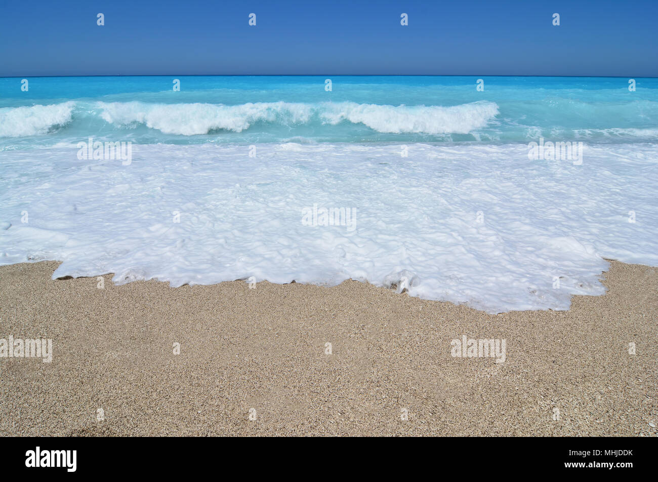 Immagine semplice di diversi strati di colore, sabbia, bianco di schiuma di mare turchese, onde e cielo blu sulla linea di orizzonte Foto Stock
