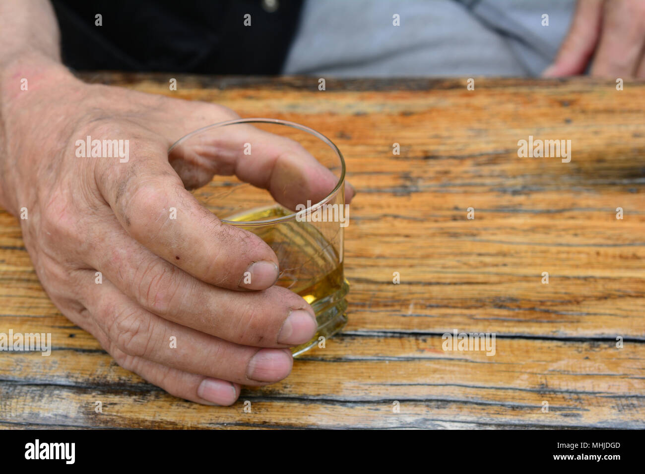 Uomo di mano che trattiene il vetro con il vecchio, buon brandy alla prugna sul vecchio, grunge tavolo in legno di quercia Foto Stock