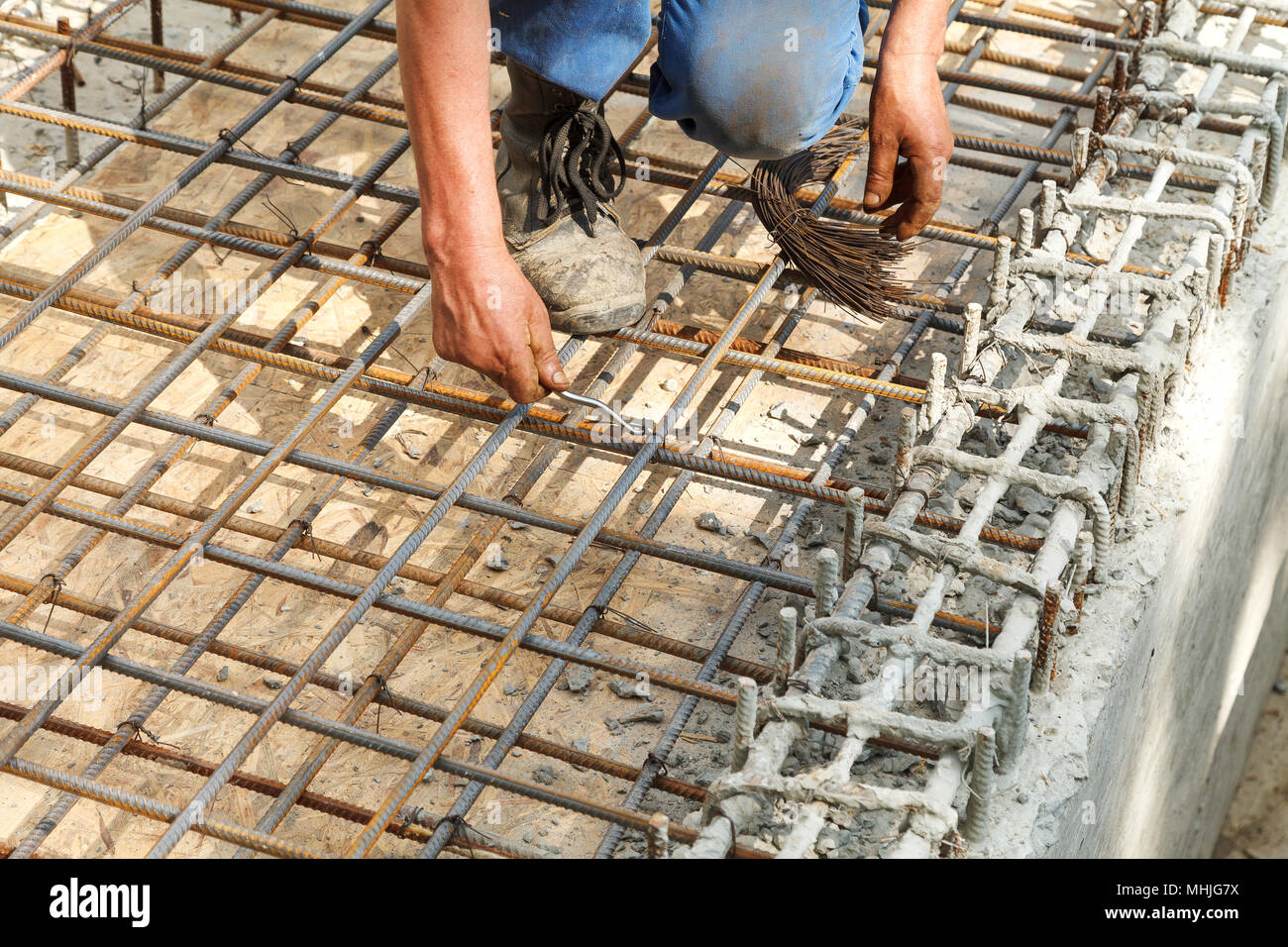 Il lavoratore tiranti in acciaio barre di rinforzo con filo per rafforzare le fondamenta. Close-up. La luce diurna. Foto Stock