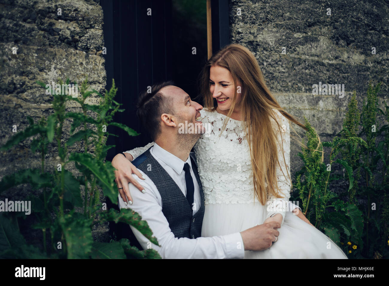Giovane elegante moda giovane in amore in Islanda. Donna e uomo abbracciare e desidera baciate. Montagne di pietra e islandese casa sullo sfondo. Foto Stock