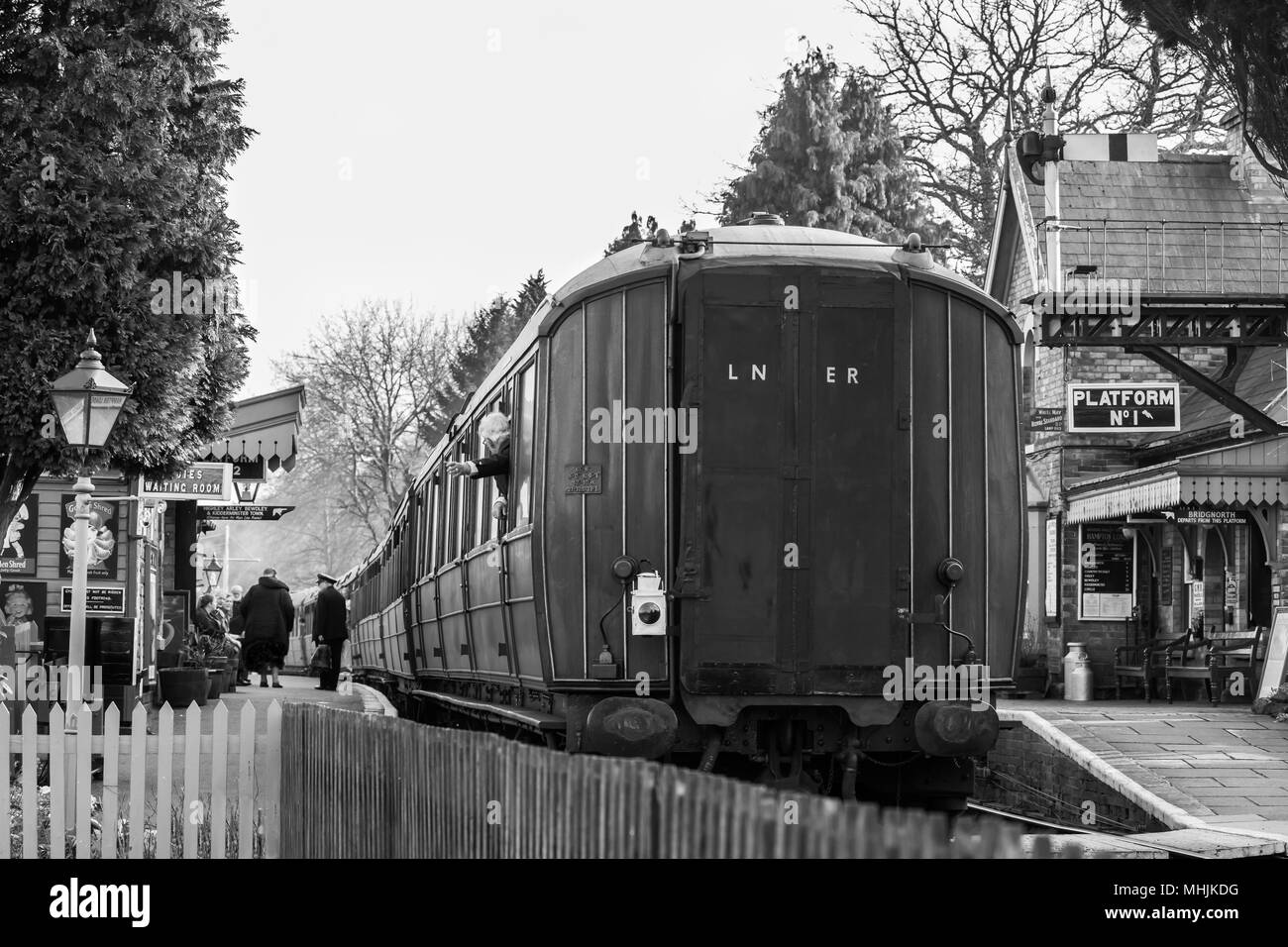 Bianco & Nero nostalgia. Vista posteriore di vintage carrozza ferroviaria tirato dal motore a vapore in attesa presso SVR Hampton Loade stazione. Onde di guardia dalla finestra. Foto Stock