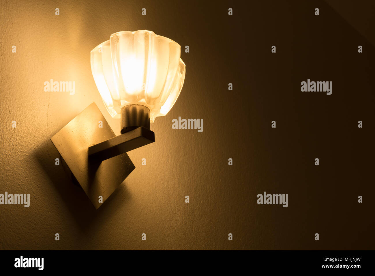 Lampada gialla illuminata, muro di cemento con lo sfondo delle lampadine. Foto Stock
