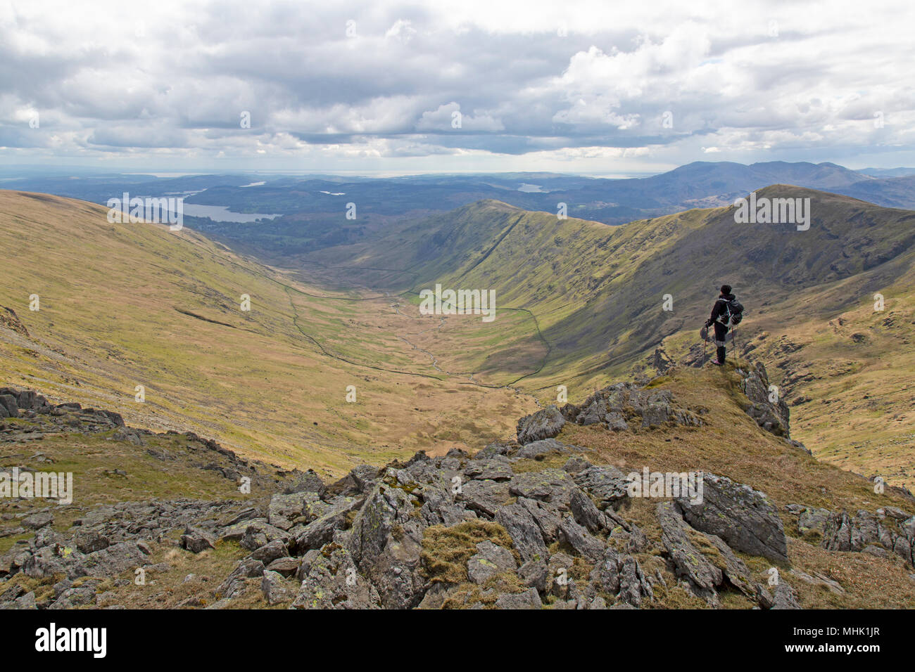 Escursionista femmina guardando attraverso le montagne del Fairfield Horseshoe trekking nel parco nazionale del Lake District in Inghilterra. Foto Stock