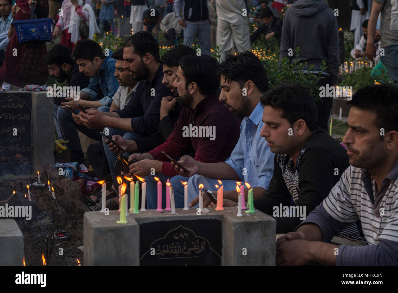 Kashmir musulmano sciita uomini recita il Corano dai loro telefoni su una tomba della loro relativa al marchio FUSC-e-barat a Srinagar, la capitale estiva della controllata indiana del Kashmir. Fusc-e-barat è giorno religioso prevalentemente osservato da Shitte comunità musulmane nella notte tra il quattordici e il quindici Sha'divieto (ottavo mese secondo calendario musulmano). I Musulmani credono questo FUSC-e-barat come una notte quando Allah può perdonare i peccatori e quando le sorti di esseri umani per il prossimo anno sono decise. In molte parti della valle del Kashmir, musulmani sono disposti preghiere per ottenere il perdono da Dio per il defunto ancesto Foto Stock