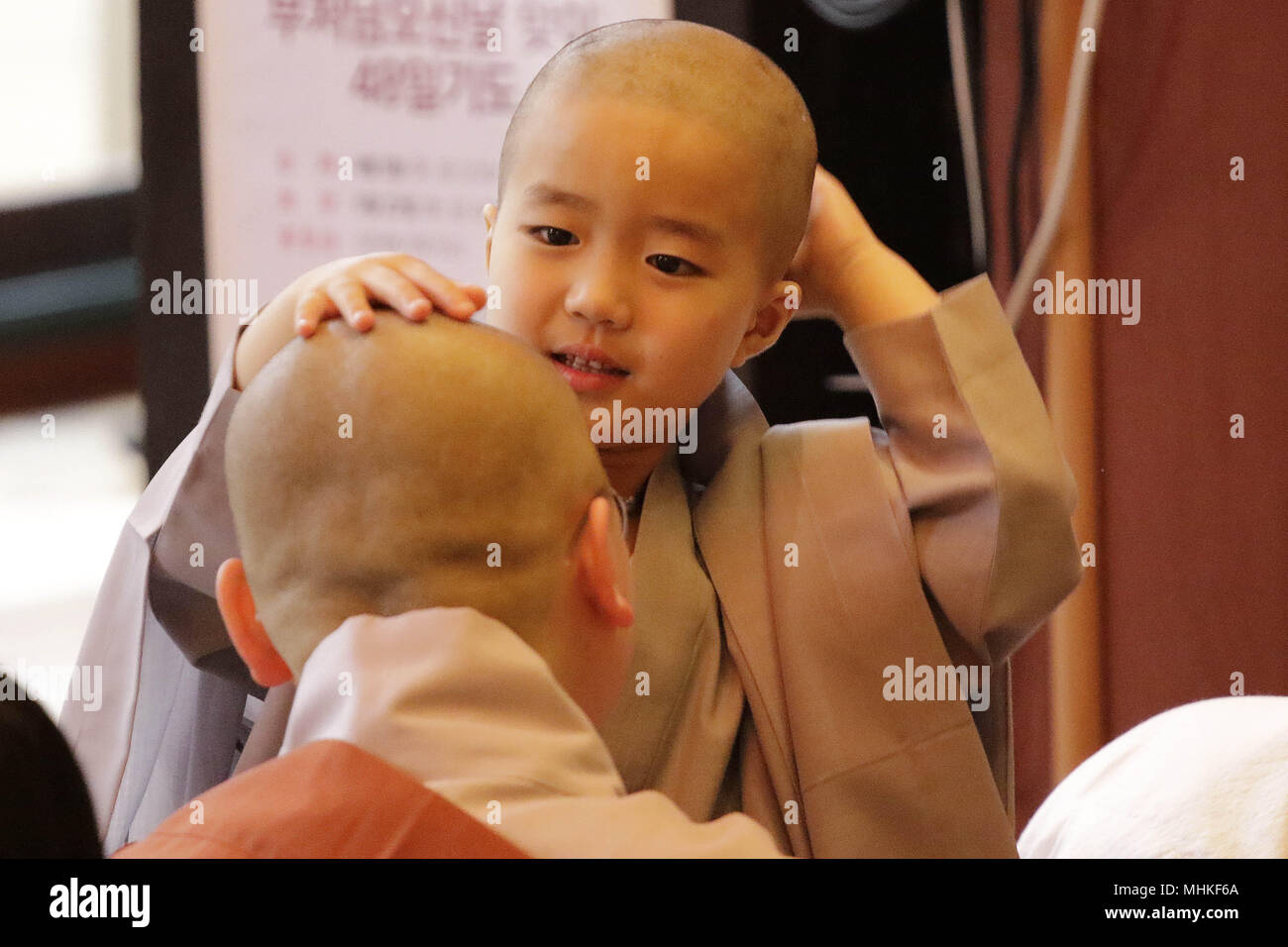 2 maggio 2018 - Seoul, Corea del Sud - 2 Maggio 2018-Seoul, Corea del Sud - un bambino prende il suo capo rasato da un monaco buddista durante il "figli di diventare monaci buddisti' cerimonia prossimo buddha il compleanno in un tempio Chogye a Seul, in Corea del Sud. I bambini hanno il loro pelo rasato off durante il "figli di diventare monaci buddisti' cerimonia davanti al buddha il compleanno in un tempio Chogye. I bambini potranno soggiornare presso il tempio di imparare circa il buddismo per 20 giorni. Il Buddha è nato circa 2,562 anni fa, e sebbene la data esatta è sconosciuta, del Buddha compleanno ufficiale è celebrata la luna piena Foto Stock