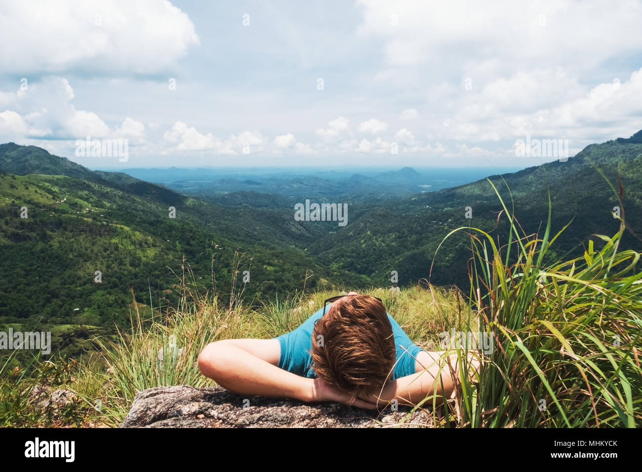 Uomo disteso su erba e cercando in bella vista della montagna in Sri lanka Foto Stock
