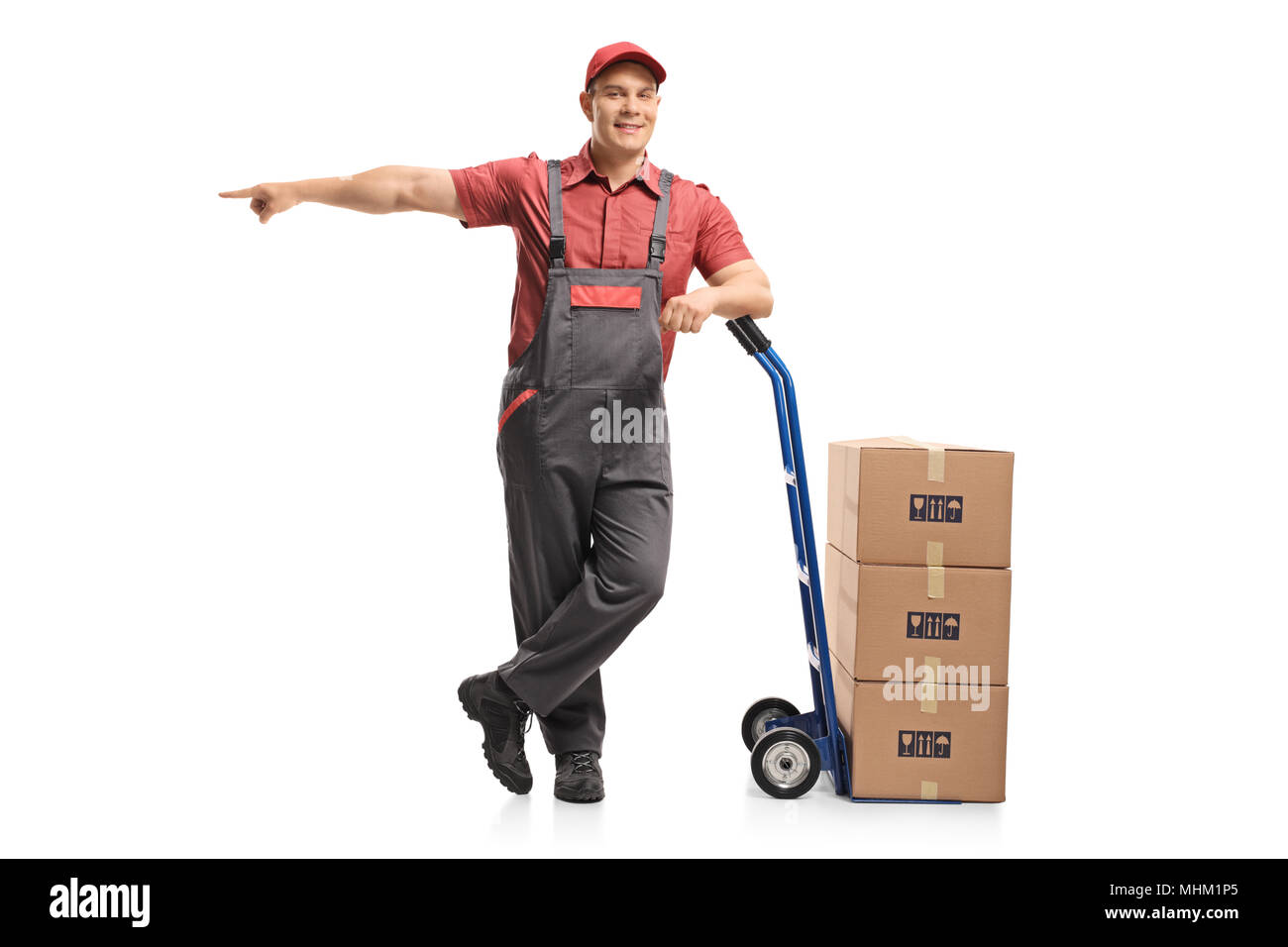 A piena lunghezza Ritratto di un mover appoggiato su di un carrello con una pila di scatole e puntamento isolati su sfondo bianco Foto Stock