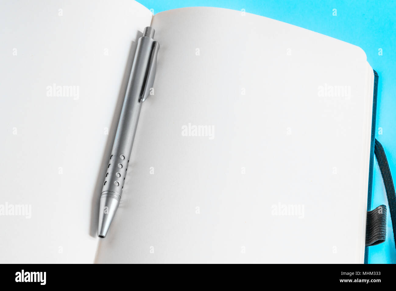 Un metallo penna biro sulle pagine vuote di un notebook su sfondo azzurro. Foto Stock