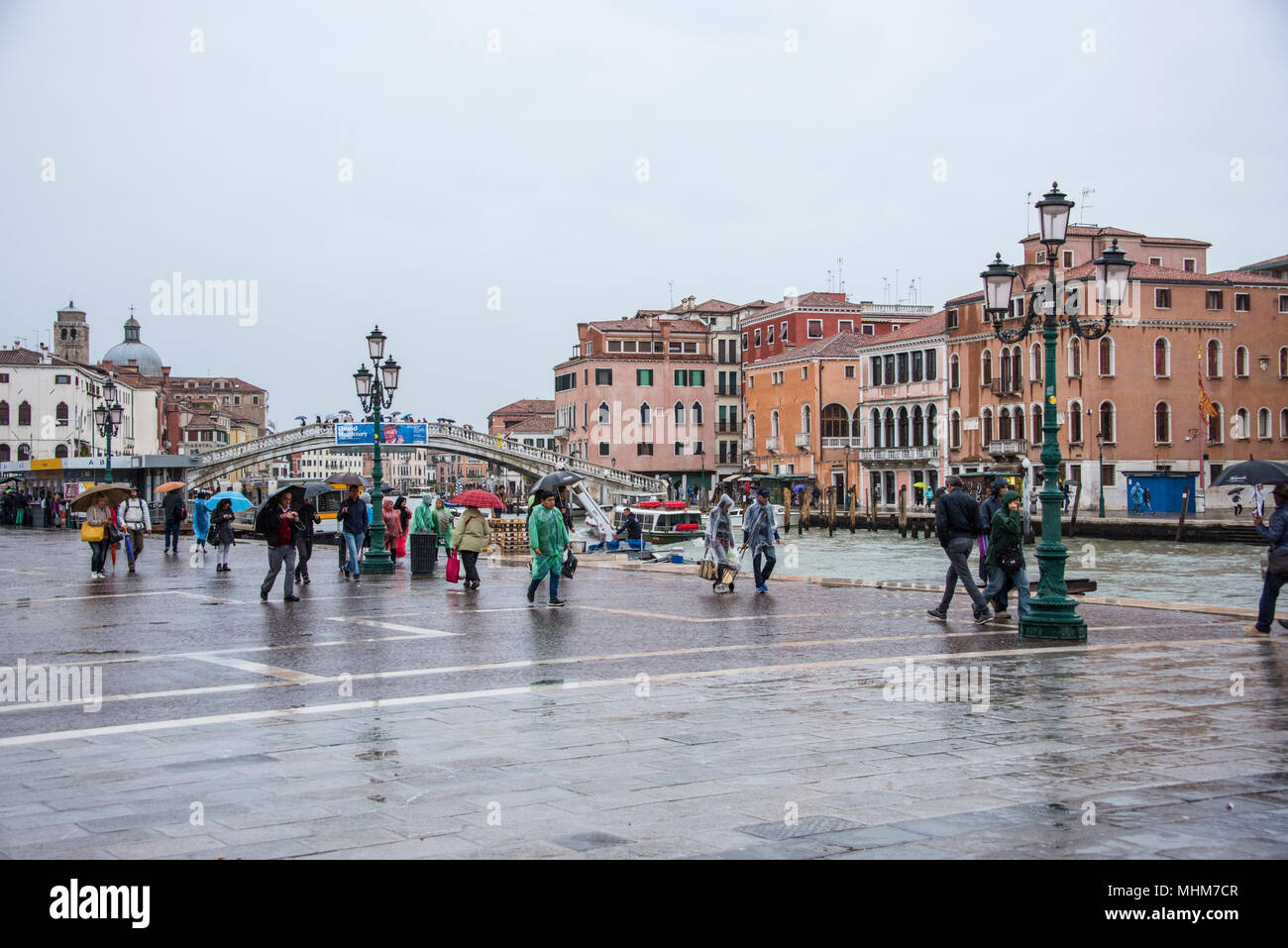 I turisti a piedi sotto la pioggia sul Canal Grande al di fuori della stazione ferroviaria di Venezia, Italia Foto Stock