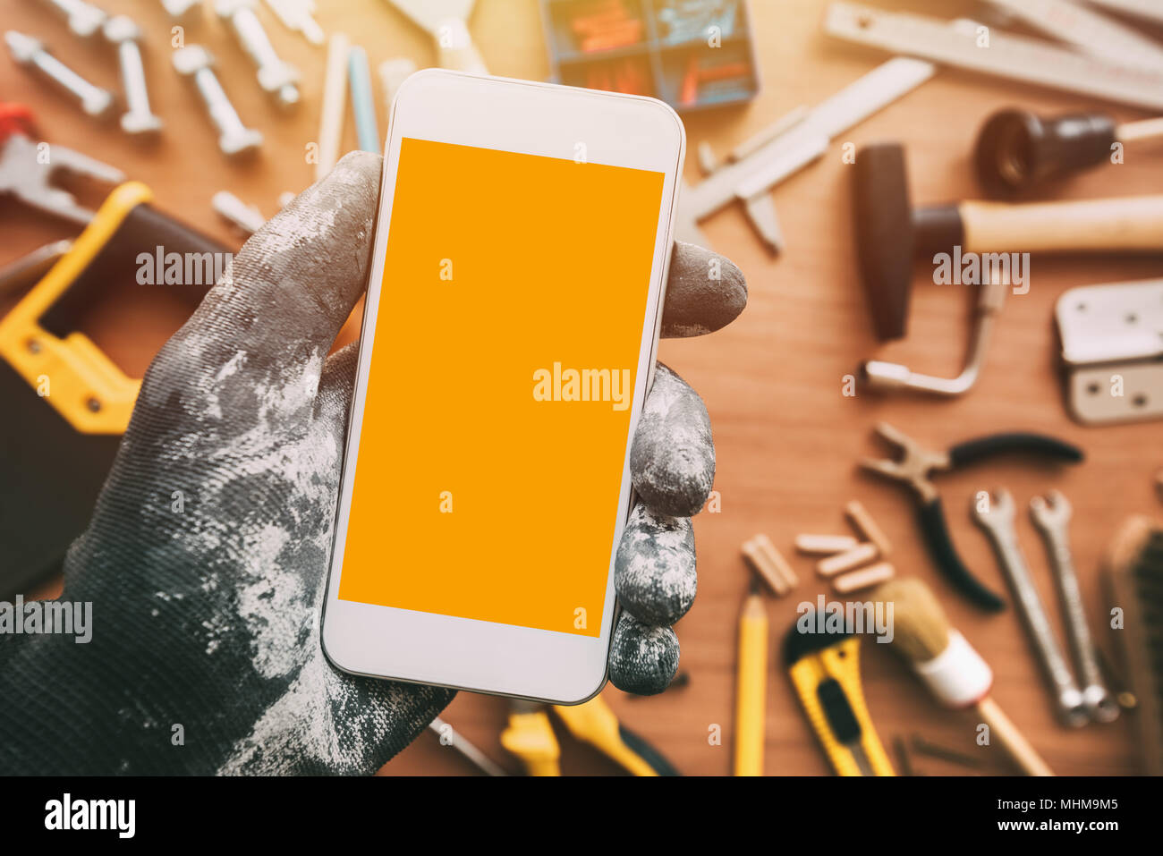 Handyworker smart phone app con schermo vuoto. Repairman tenendo il telefono cellulare in mano. Copia spazio per testo, vista dall'alto Foto Stock