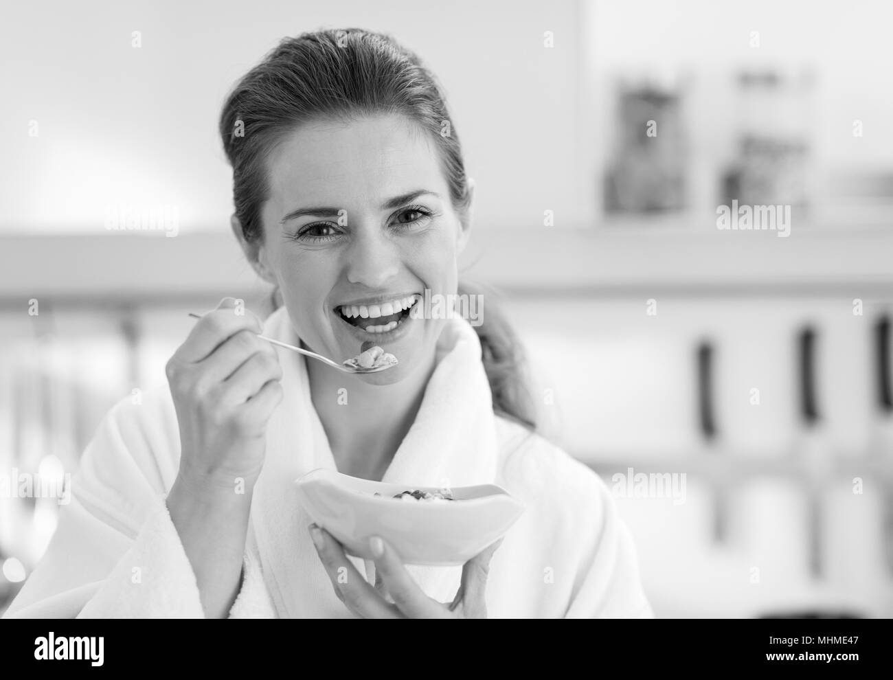 Sorridente giovane donna in accappatoio avente una sana prima colazione Foto Stock