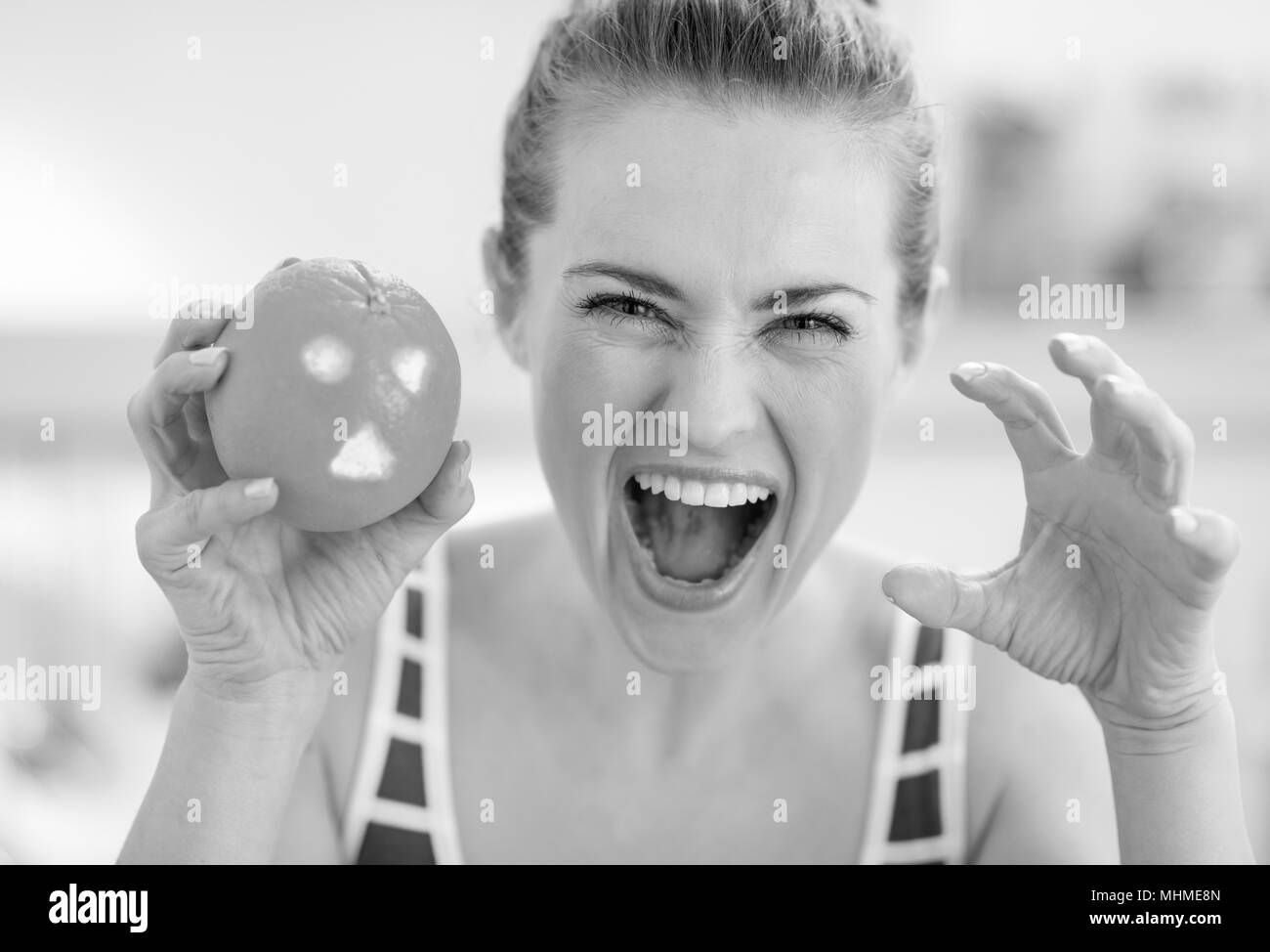 Giovane donna a spaventare con orange con santificare faccia Foto Stock