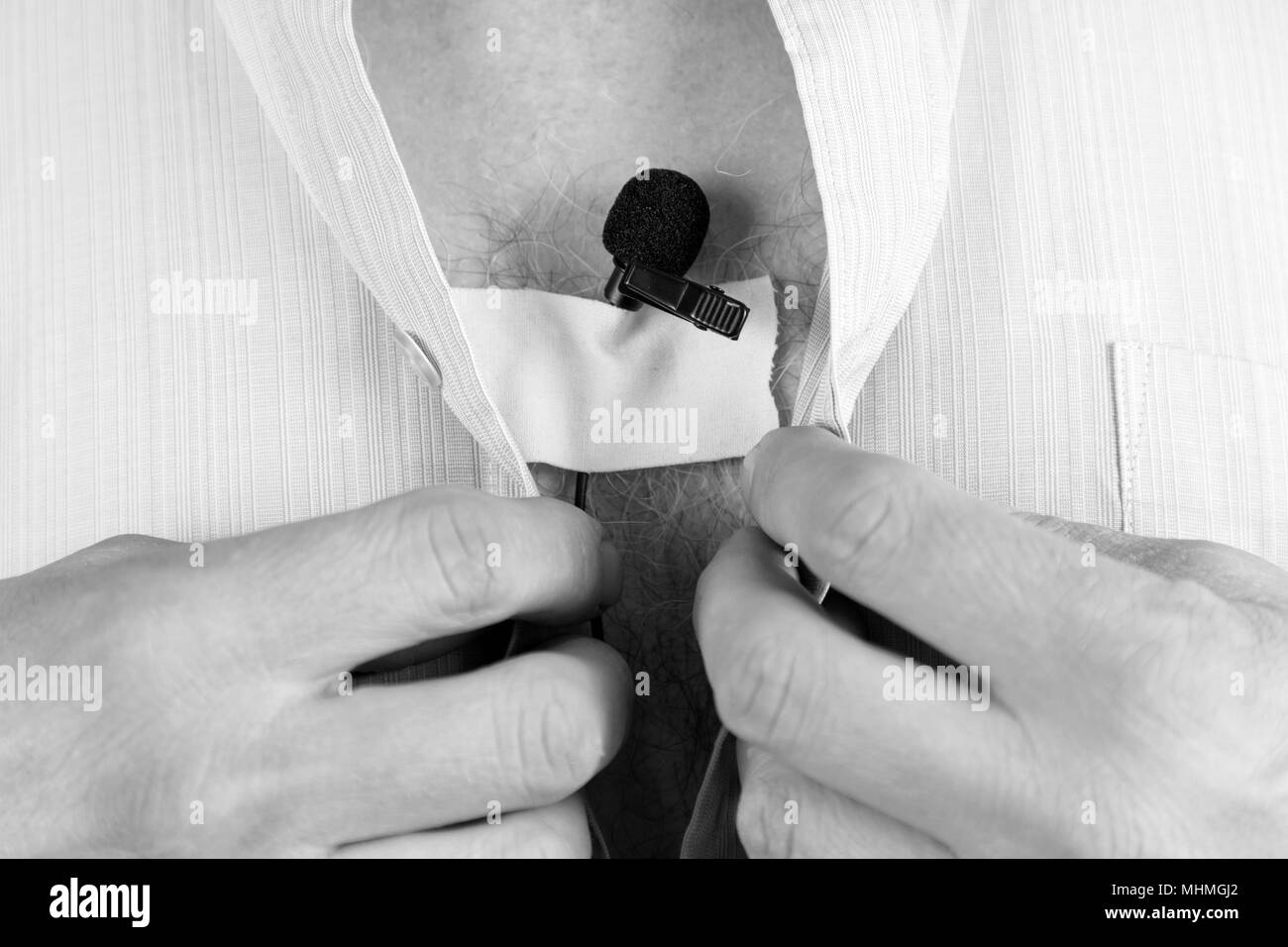 Un detective privato mette su un piccolo microfono un occhiello sotto la sua camicia segreto per la registrazione del suono. Foto Stock