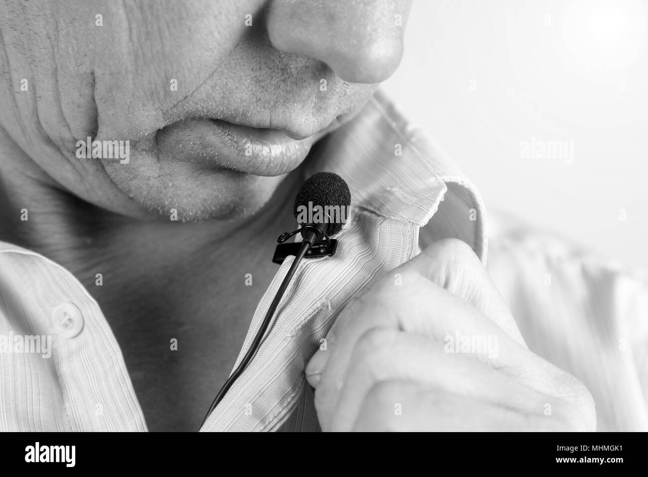 Le labbra di un uomo parlare ad alta voce in un sussurro in un microfono da bavero. Foto Stock