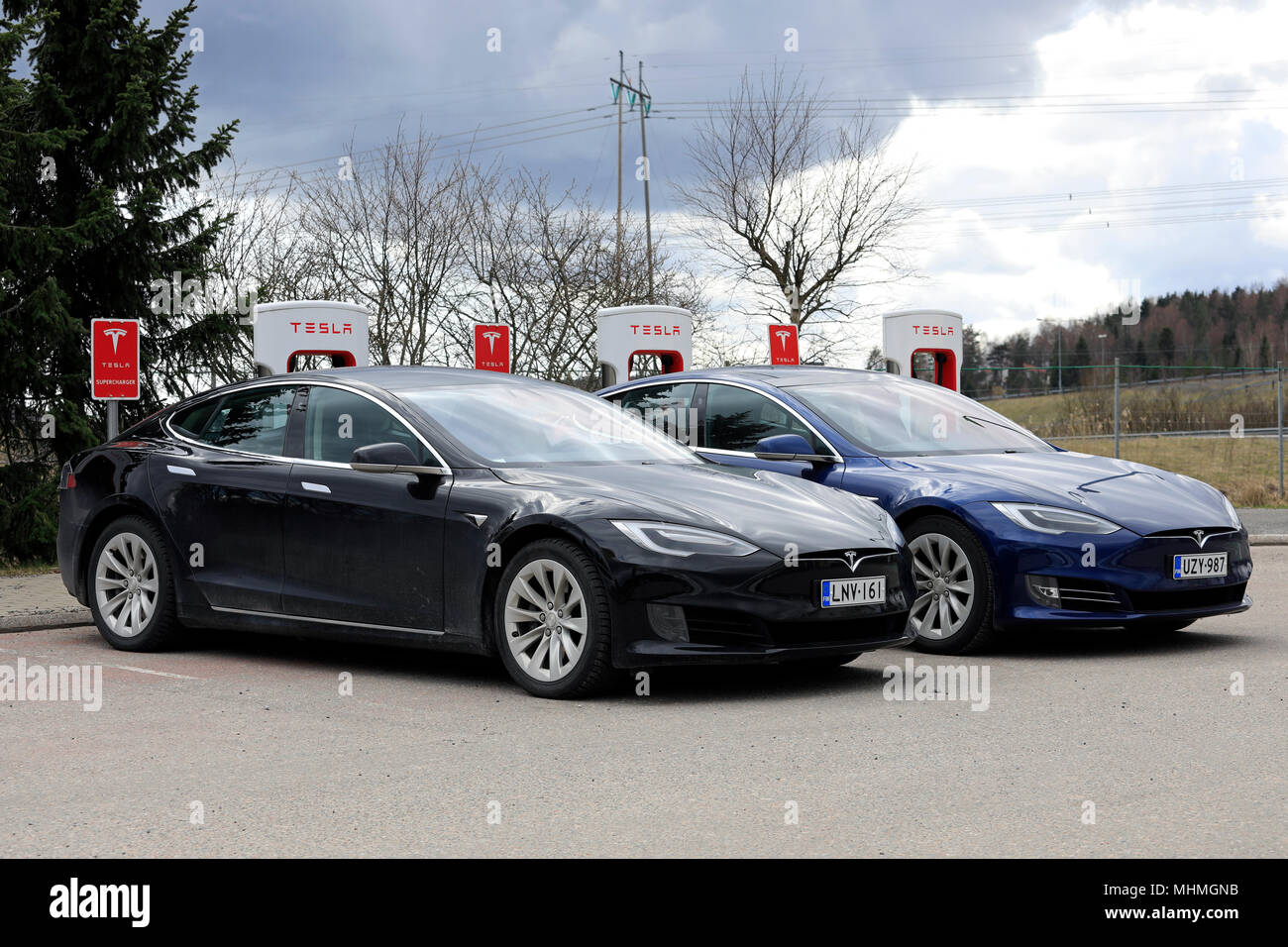 Due Tesla Model S le automobili elettriche del aggiornato o lifting del design esterno sono in carica batteria a Supercharger station su un giorno di primavera in Paimio, Foto Stock