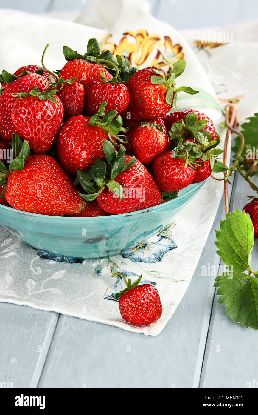 Fresche fragole mature in un bel blu ciotola con il fuoco selettivo e di estrema profondità di campo. Foto Stock