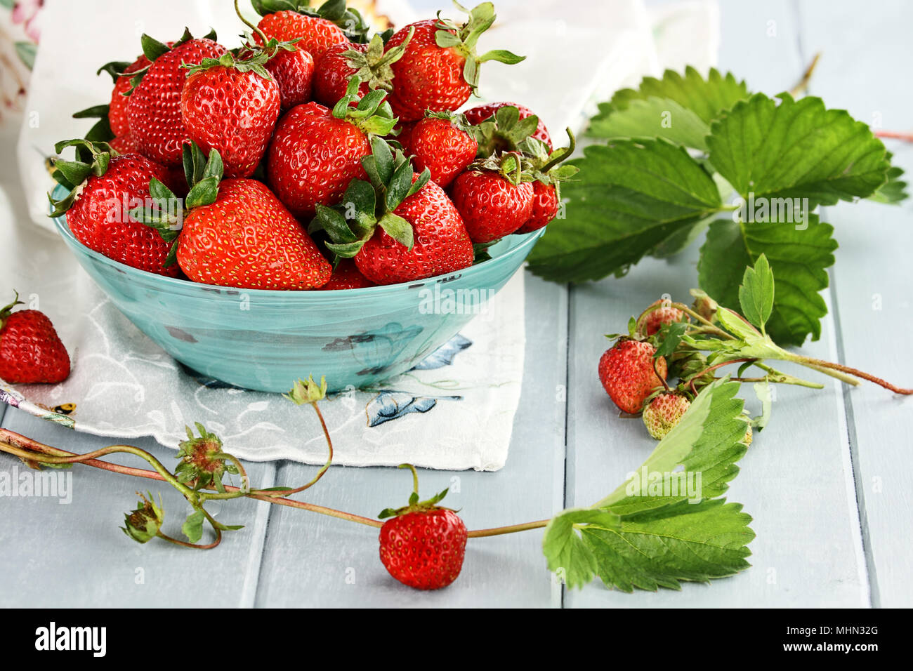 Fresche fragole mature in un bel blu ciotola con il fuoco selettivo e di estrema profondità di campo. Foto Stock