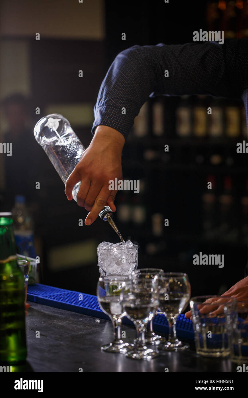 Barista riversa sciroppo in bicchiere da cocktail presso un banco di bar Foto Stock